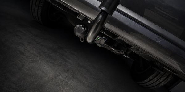 Close-up of a car's exhaust pipe and rear tires in a dimly lit garage.