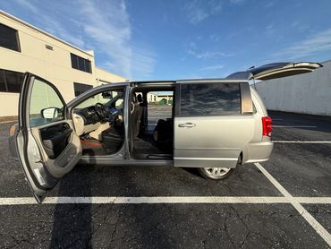 Silver minivan with doors and trunk open in a parking lot.