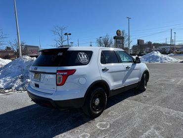 White Ford SUV taxi parked in a snowy lot under clear blue sky.