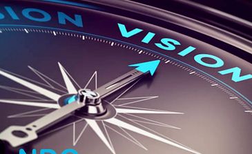 Close-up of a compass needle pointing to the word 'VISION'.