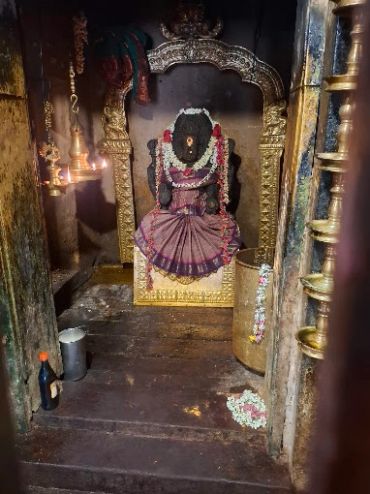 Ancient deity statue adorned with flowers and cloth.