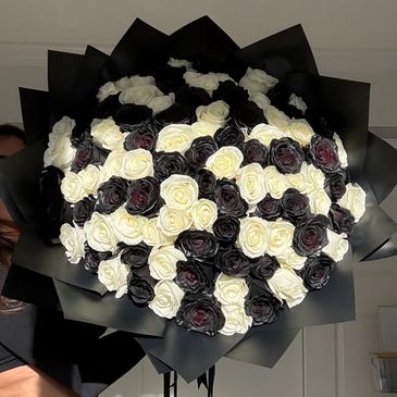 Bouquet of black and white roses wrapped in black paper.