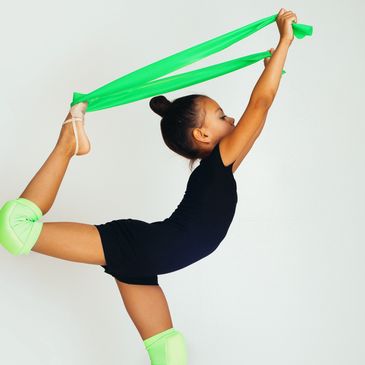 young rhythmic gymnast stretching the leg with a stretchband developing flexibility