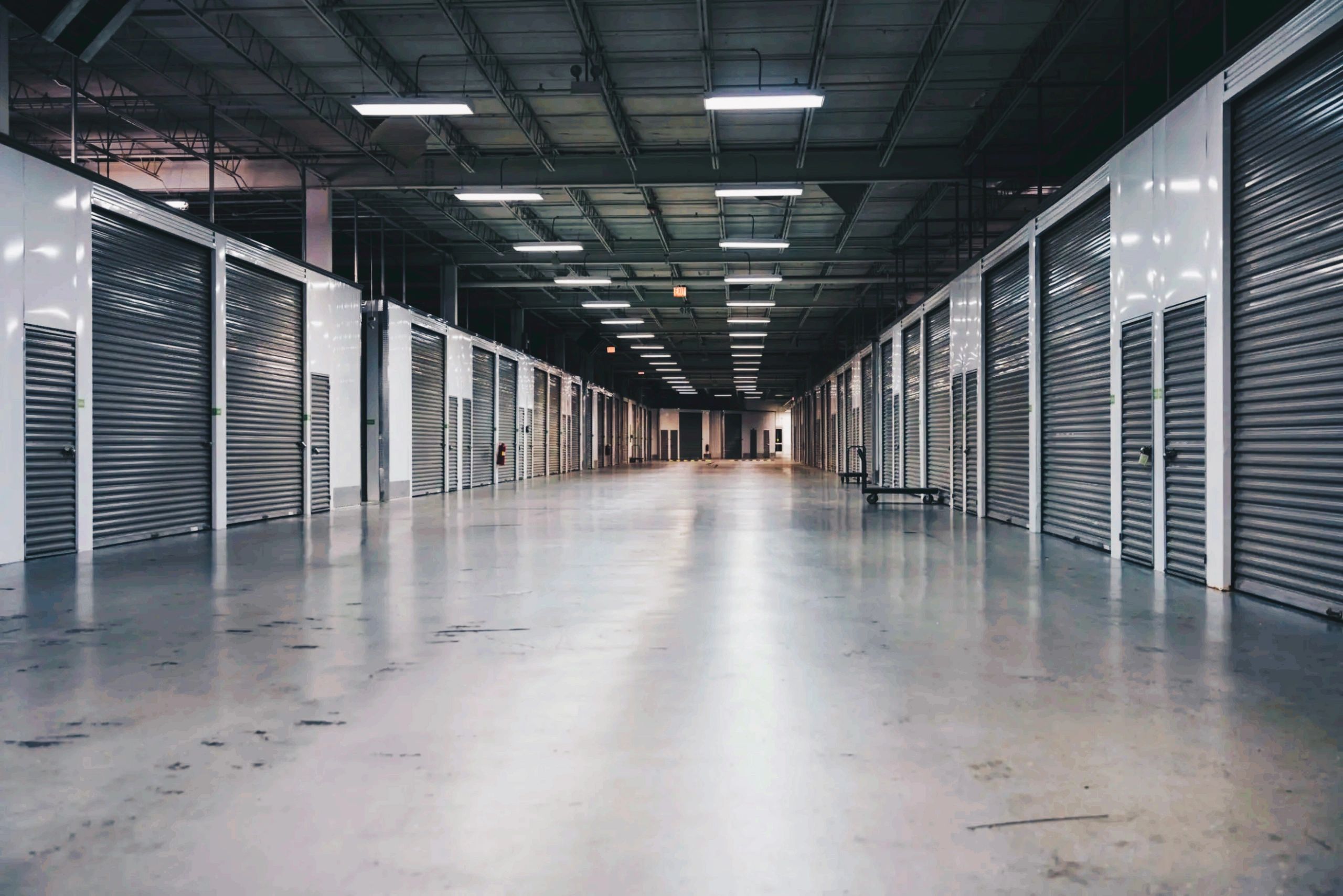 A spacious indoor storage facility with multiple closed metal roll-up doors.