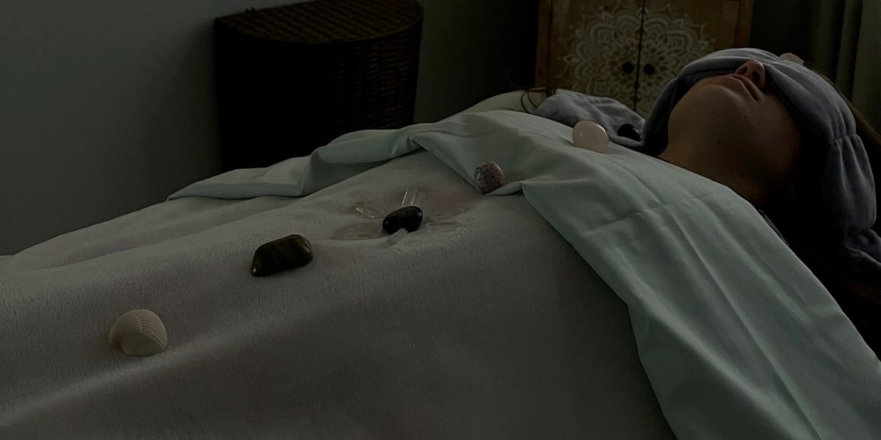 Person lying down with crystals on their body and an eye mask.