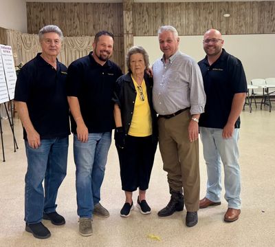 Five adults posing in a community hall, smiling at the camera.