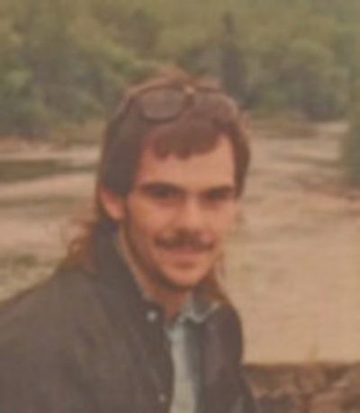 A man with glasses on his head by a river.