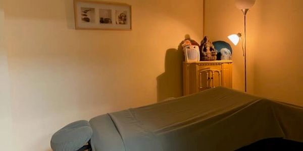 A cozy massage room with a massage table and soft lighting.