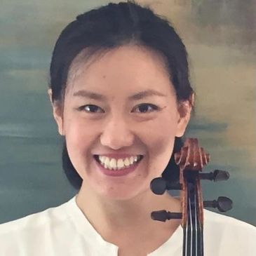 Smiling woman holding a violin in front of a muted background.