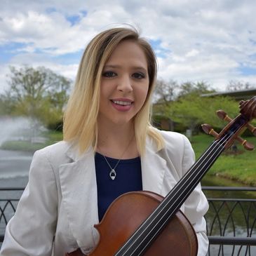 Young woman holding a cello near a fountain outdoors.