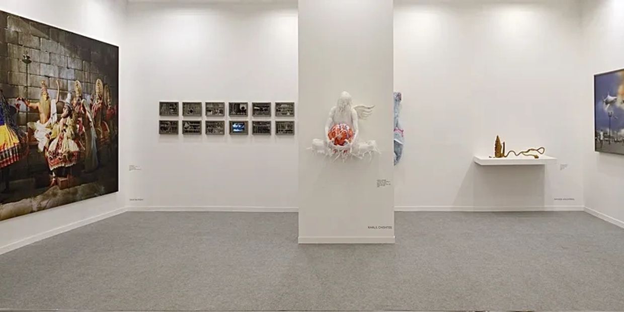 Art gallery with diverse paintings and sculptures on white walls.