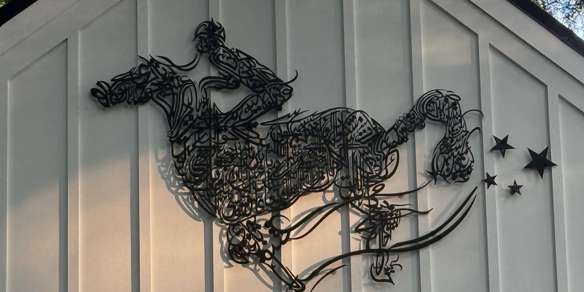 Metal artwork of a unicorn with stars on a white wall.