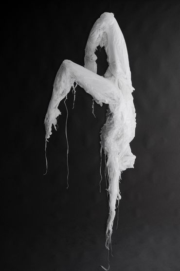Sculpture by Khalil Chishtee. A humanoid figure suspended mid-air made of white plastic trash bags.
