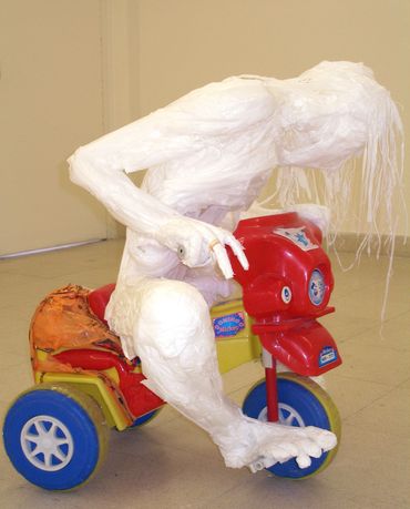 White plastic bag sculpture of an adult, hunched over, riding a toy bike.