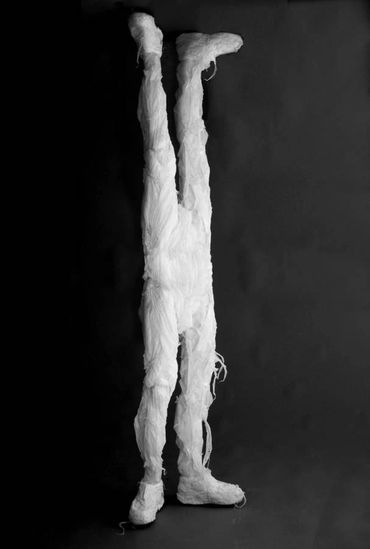 Humanoid sculpture with a second pair of legs replacing the upper body, made from white trashbags.