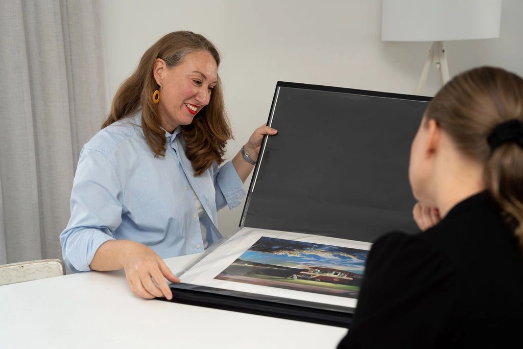 Woman showing an art portfolio to another person.