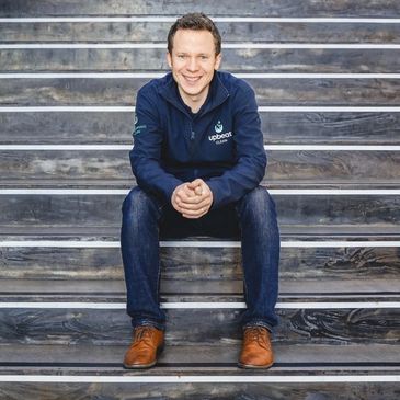 Man in casual wear sitting on stairs, smiling at the camera.