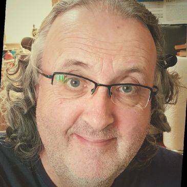 Smiling middle-aged man with glasses and curly gray hair.