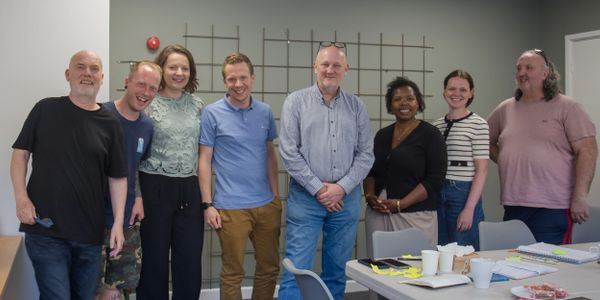 A diverse group of eight people smiling in a casual meeting room.