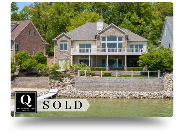 Spacious lakeside house with stone facade and large balcony, marked as sold.