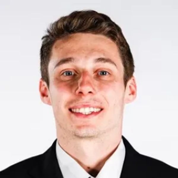 Young man in a suit and tie smiling at the camera.