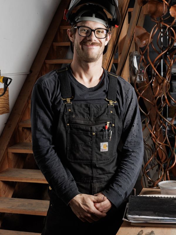 Smiling man in black work overalls and safety helmet.