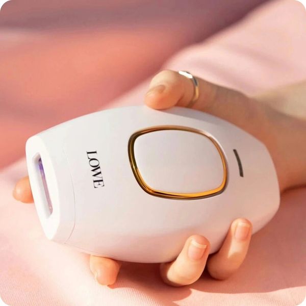 Hand holding a white LOWE branded device with gold accents.