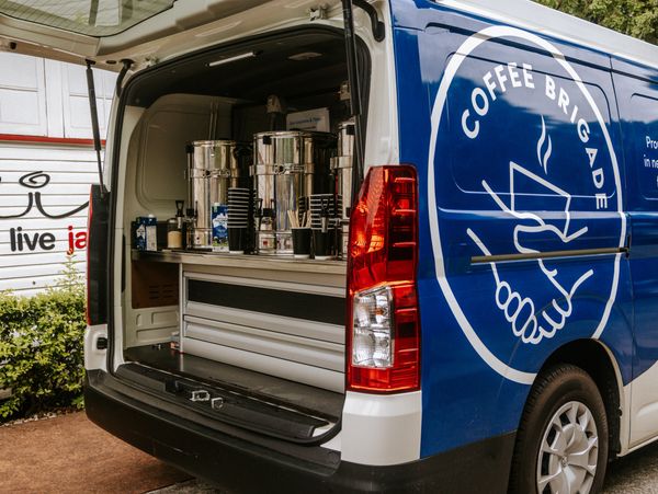 Coffee Brigade van with the back hatch open, showing urns and milk and coffee making supplies
