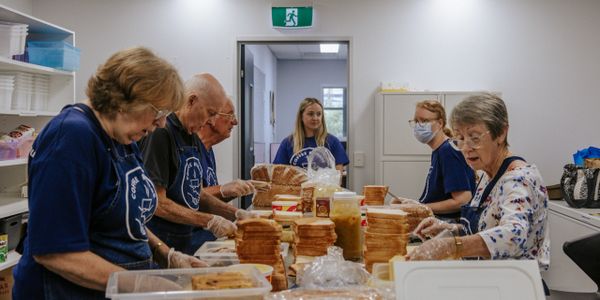 A team of sandwich-making volunteers butter bread and make fresh sandwiches in the kitchen