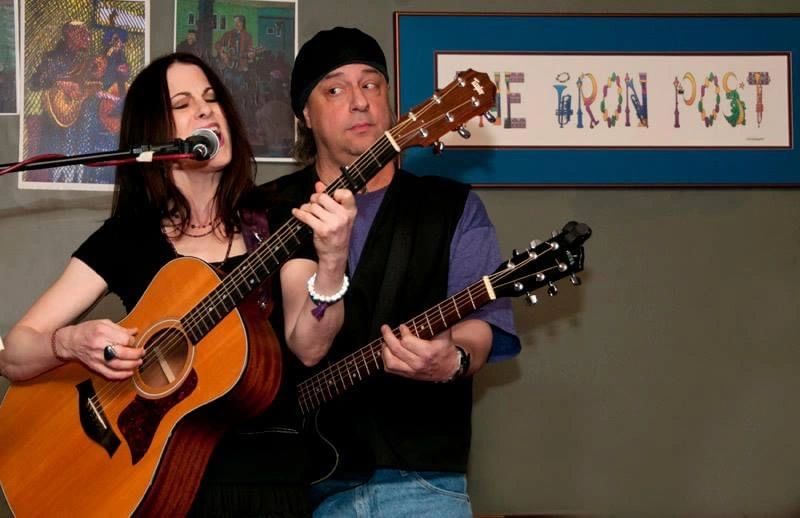 Two musicians passionately playing acoustic guitars during a live performance.