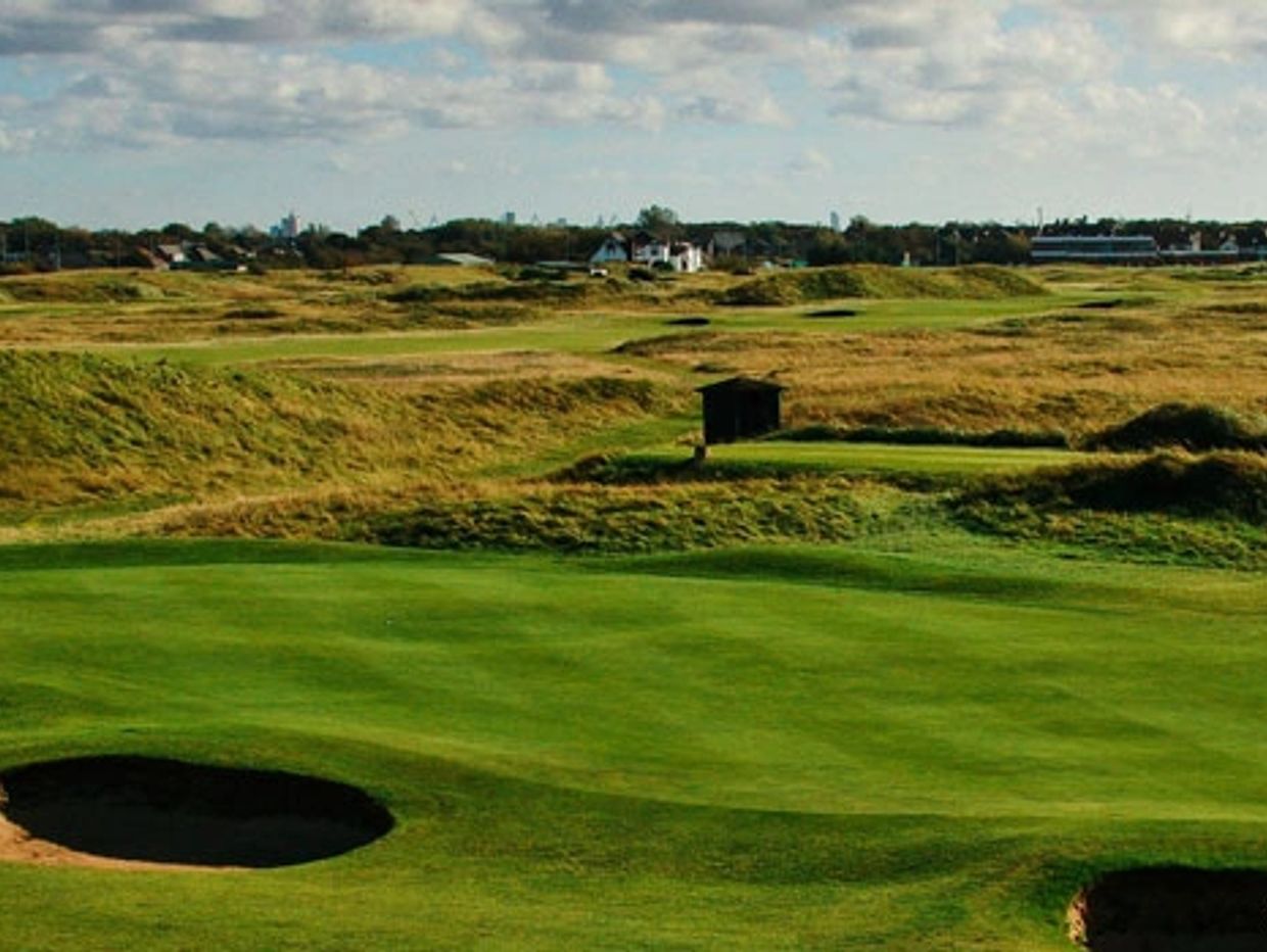 Wide view of a golf course with sand bunkers and green grass.