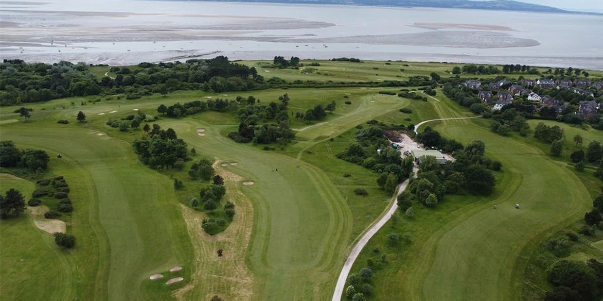 Aerial view of a green golf course by the coast.