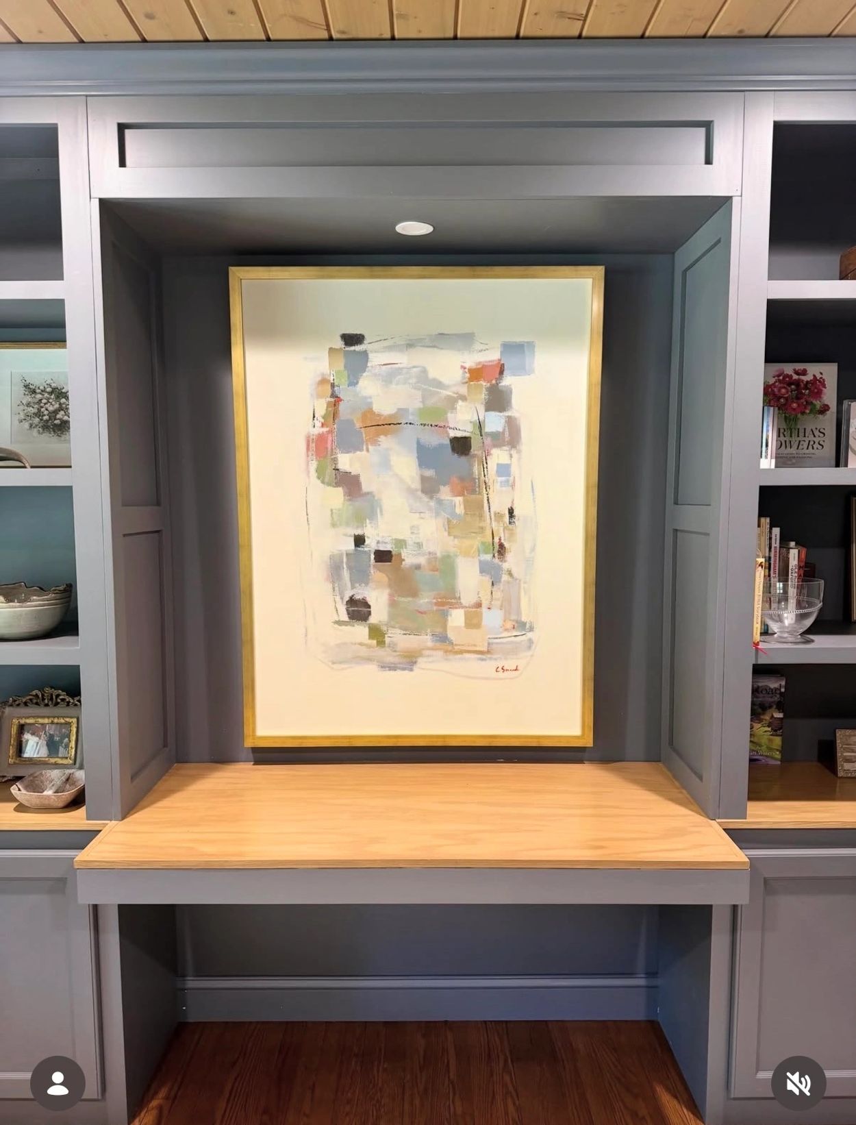 Abstract painting in a framed niche with shelves.
