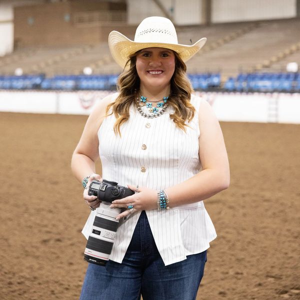 Woman with camera wearing a white hat and turquoise jewelry.