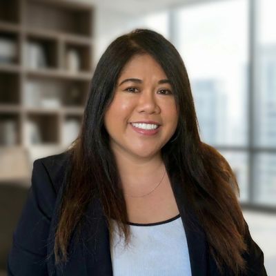Smiling woman with long dark hair in a professional office setting.
