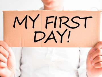 Person holding a cardboard sign that says 'MY FIRST DAY!'