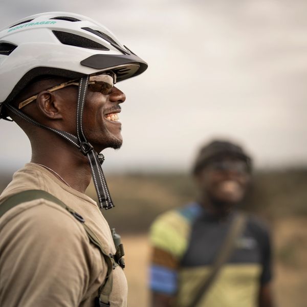 Smiling cyclist wearing a white helmet and sunglasses.