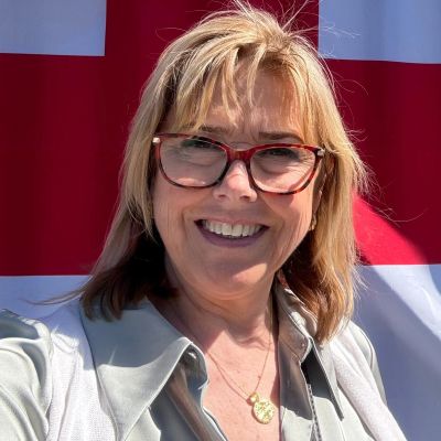 Smiling woman with glasses in front of a red and white background.