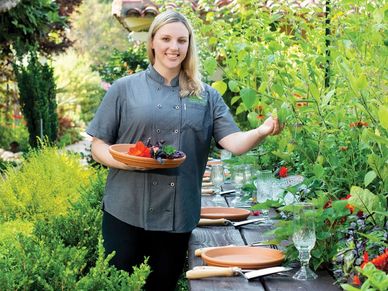 Chef Jessica Roy in Sherman Gardens smiling and picking produce