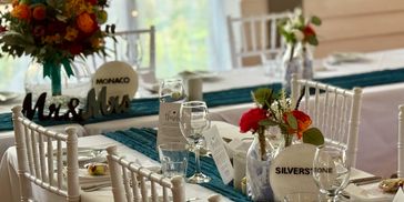 Elegant dining setup with chaivari chairs and floral centerpieces.