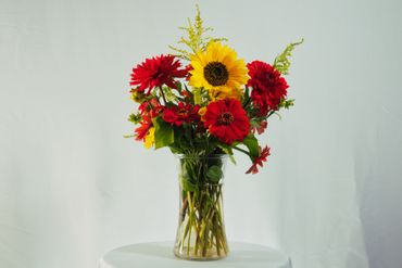 Bright bouquet of red and yellow flowers in a clear vase.