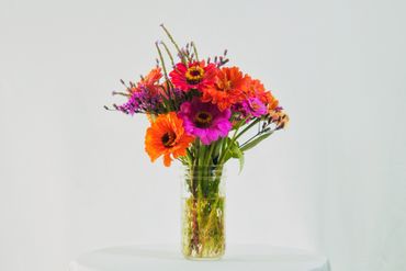 Bright bouquet of orange and purple flowers in a clear glass vase.