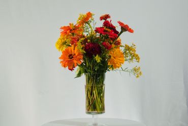 Vibrant bouquet of orange, red, and yellow flowers in a clear glass vase.