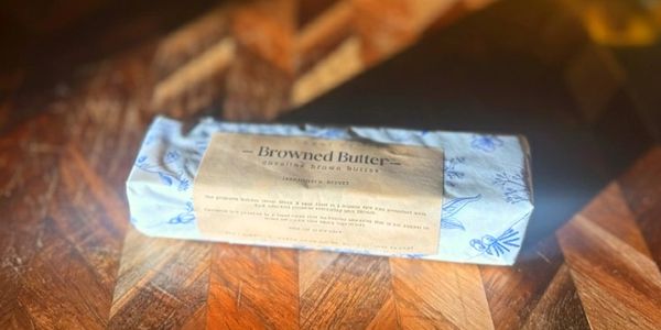 A stick of Umami Me brown butter on cutting board in sunlight