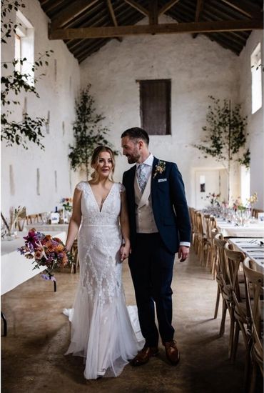 Bride and groom holding hands in a rustic wedding venue.