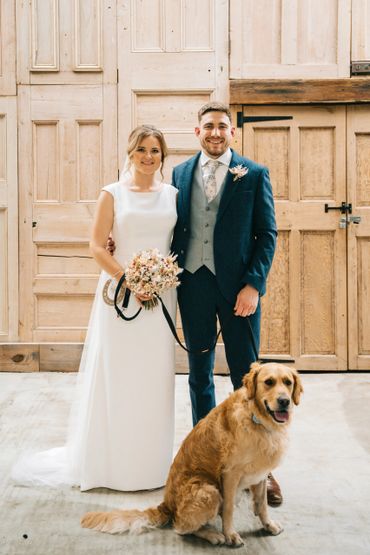 Bride and groom with their golden retriever on a wedding day.