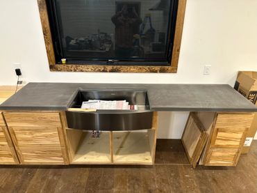 Modern wooden cabinet with a concrete countertop and an open drawer filled with papers.