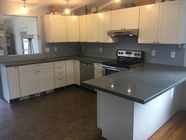 Modern kitchen with white cabinets and gray countertops.