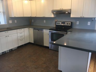 Modern kitchen with white cabinets and stainless steel appliances.