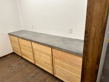 Long wooden cabinet with a smooth gray countertop in a minimalist room.